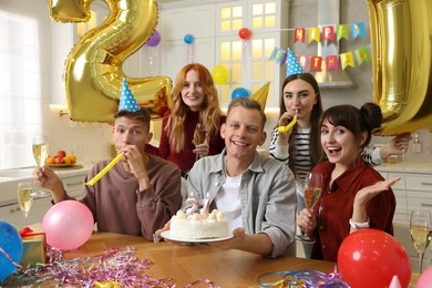 Photo of 21st birthday. Group of happy friends with tasty cake having coming of age party at home