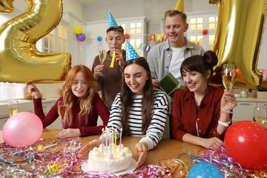 Photo of 21st birthday. Group of happy friends with tasty cake having coming of age party at home