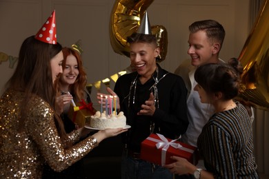 Photo of 21st birthday. Group of happy friends with tasty cake having coming of age party at home