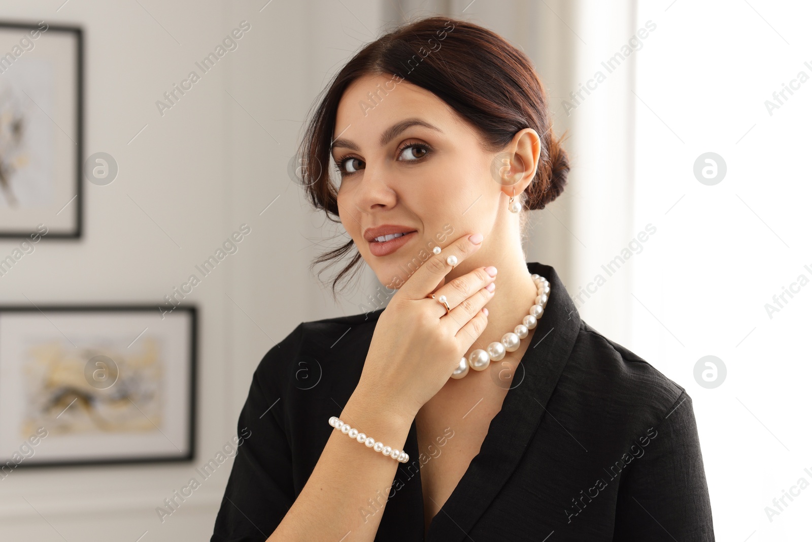 Photo of Beautiful young woman wearing elegant pearl jewelry indoors