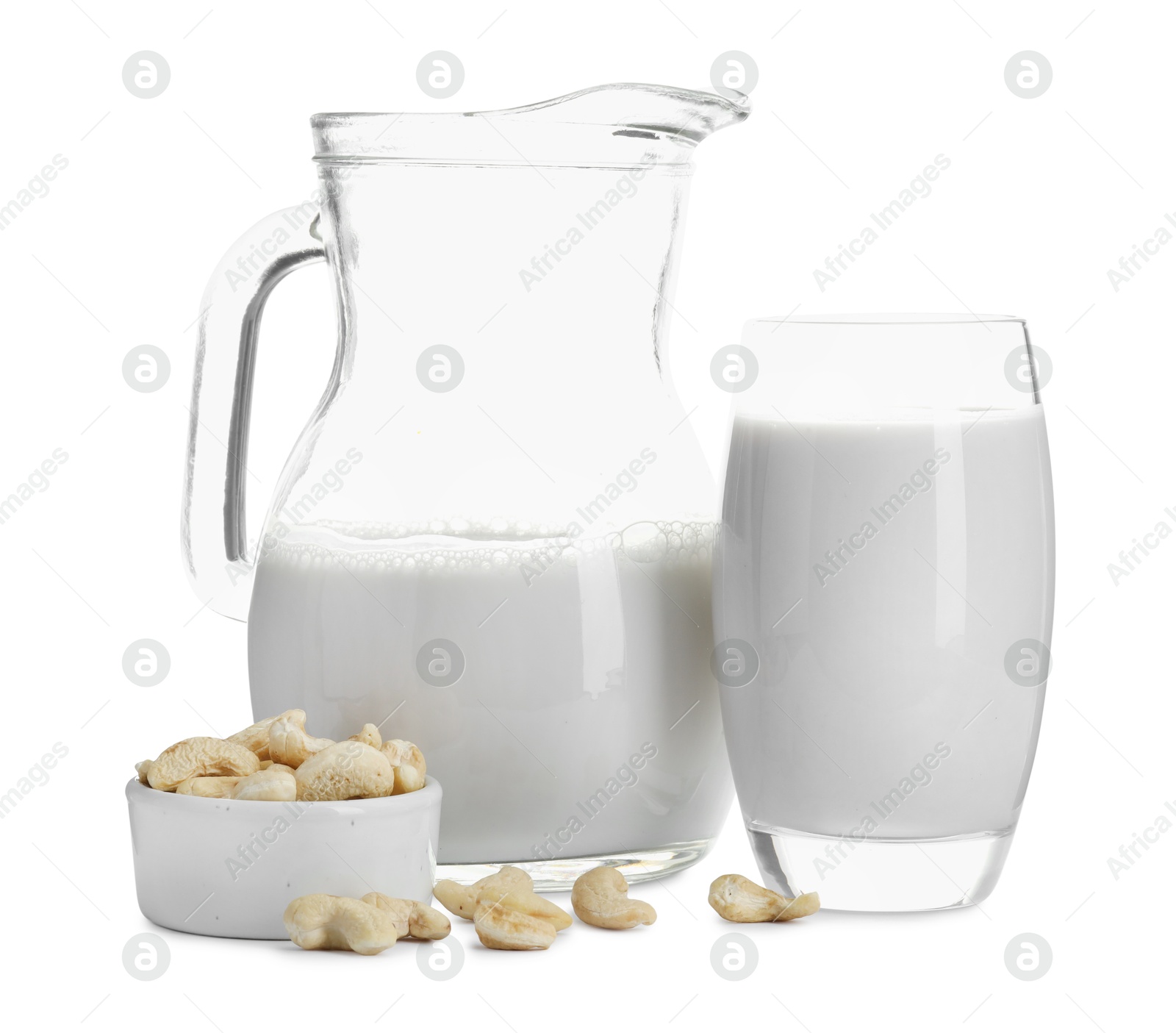 Photo of Fresh cashew milk in glass, jug and nuts isolated on white