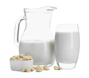 Photo of Fresh cashew milk in glass, jug and nuts isolated on white