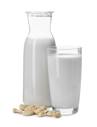 Fresh cashew milk in glass, carafe and nuts isolated on white