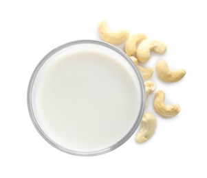 Fresh cashew milk in glass and nuts isolated on white, top view