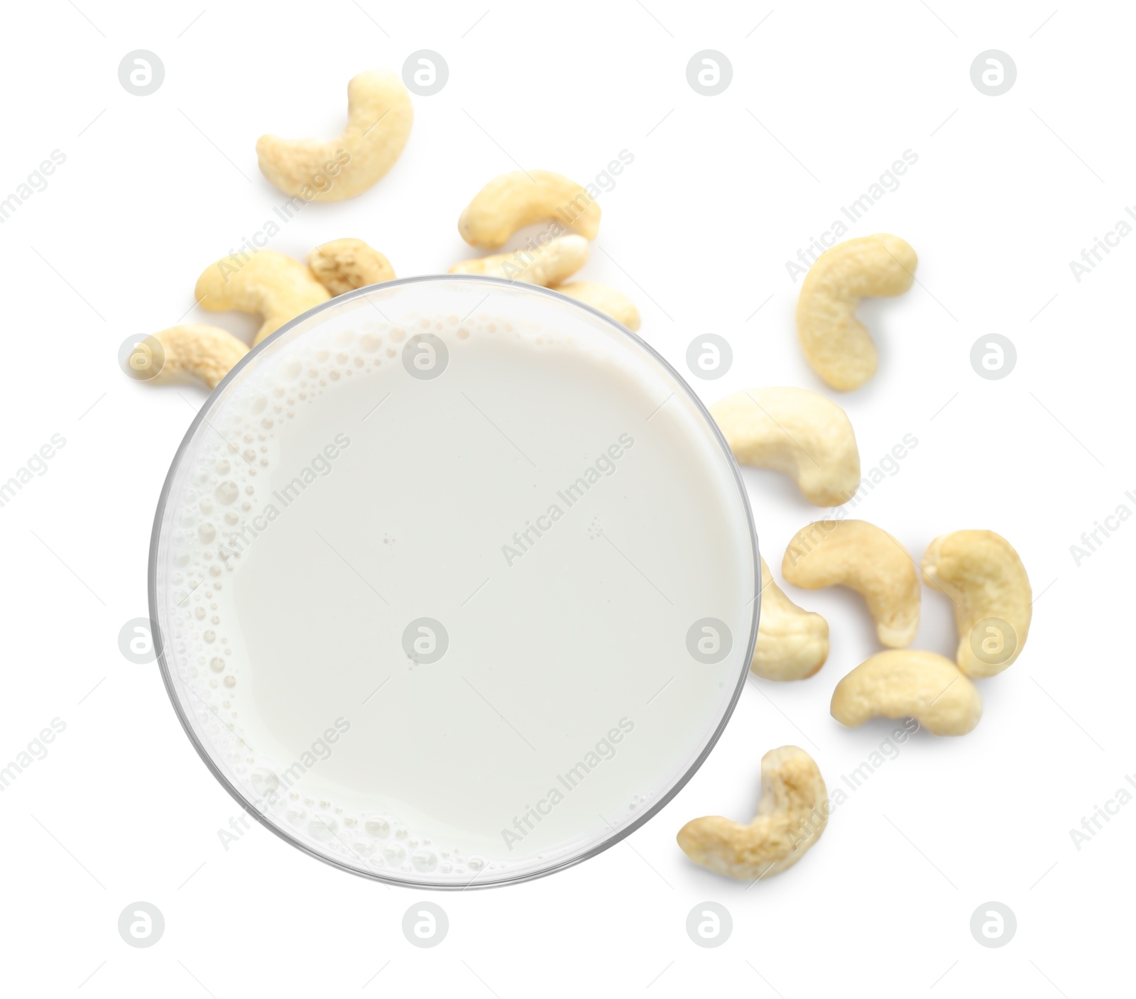 Photo of Fresh cashew milk in glass and nuts isolated on white, top view