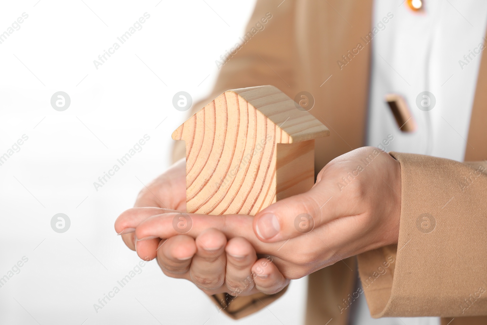 Photo of Property insurance. Real estate agent with wooden house figure on light background, closeup