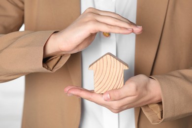 Photo of Property insurance. Real estate agent protecting wooden house figure, closeup