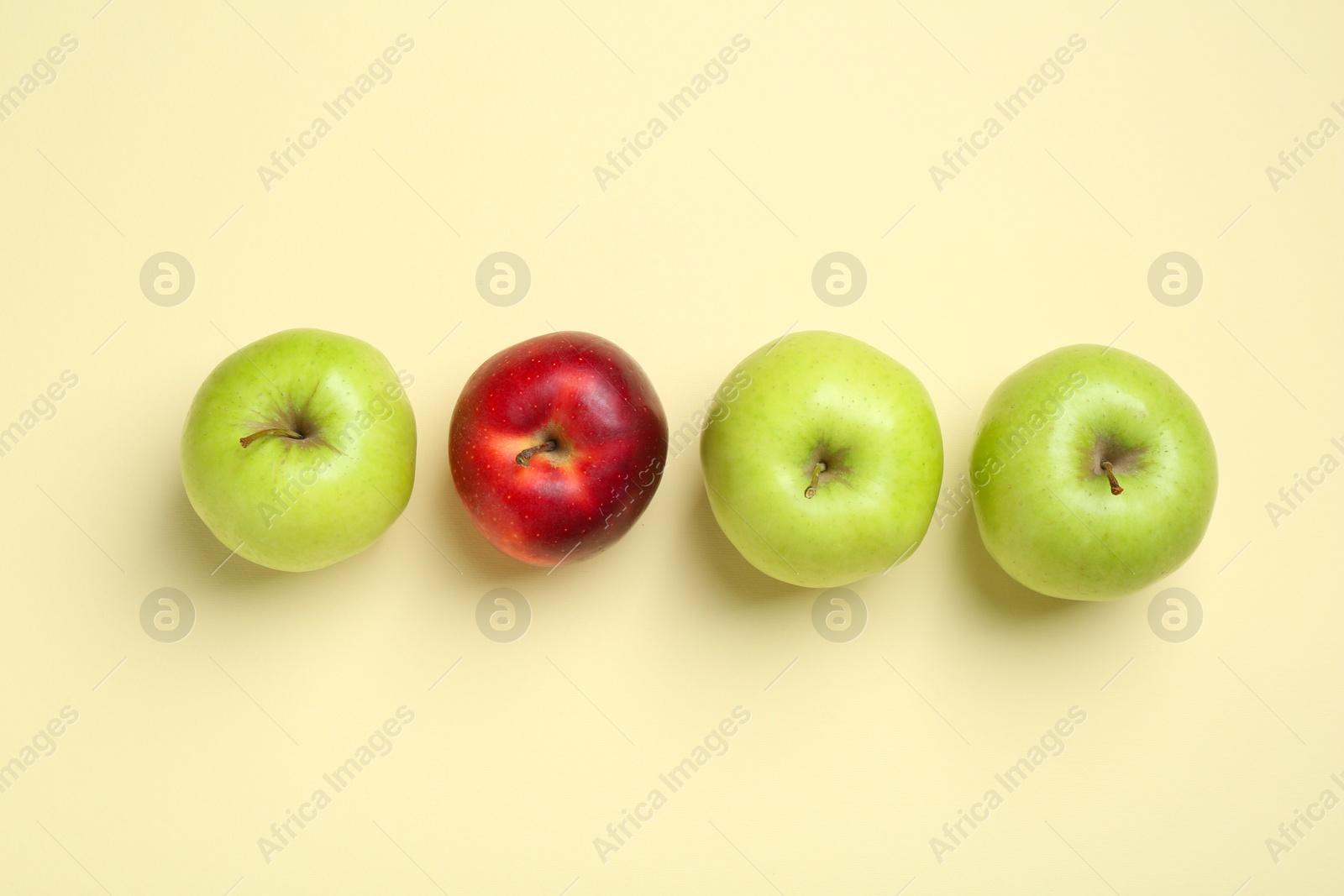 Photo of Green apples and red one on beige background, flat lay