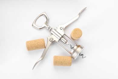 Photo of Wing corkscrew and corks on white background, top view