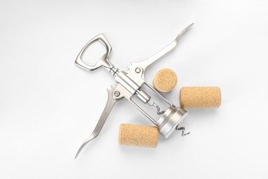 Photo of Wing corkscrew and corks on white background, top view