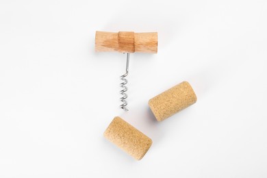 Photo of Corkscrew and corks on white background, top view