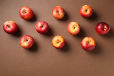 Photo of Ripe red apples on brown background, flat lay