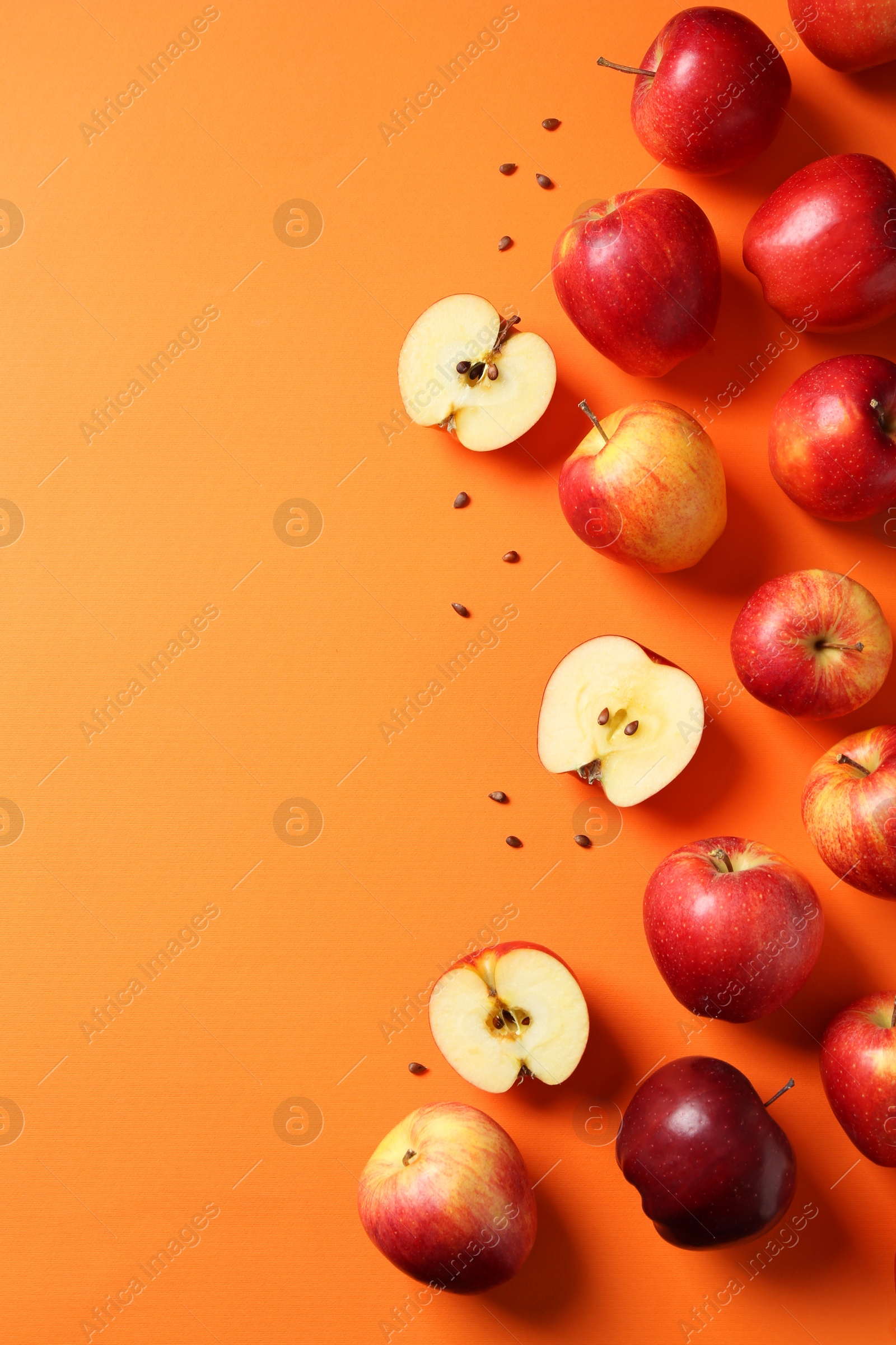 Photo of Fresh red apples and seeds on orange background, flat lay