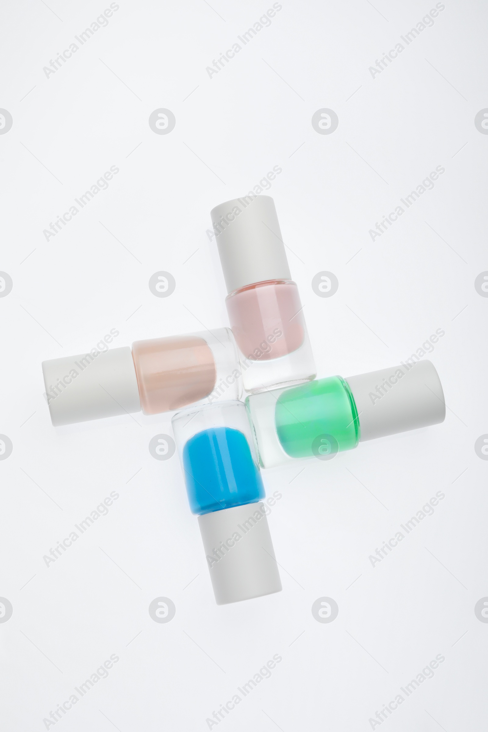 Photo of Nail polishes in bottles on white background, top view