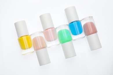 Photo of Nail polishes in bottles on white background, top view