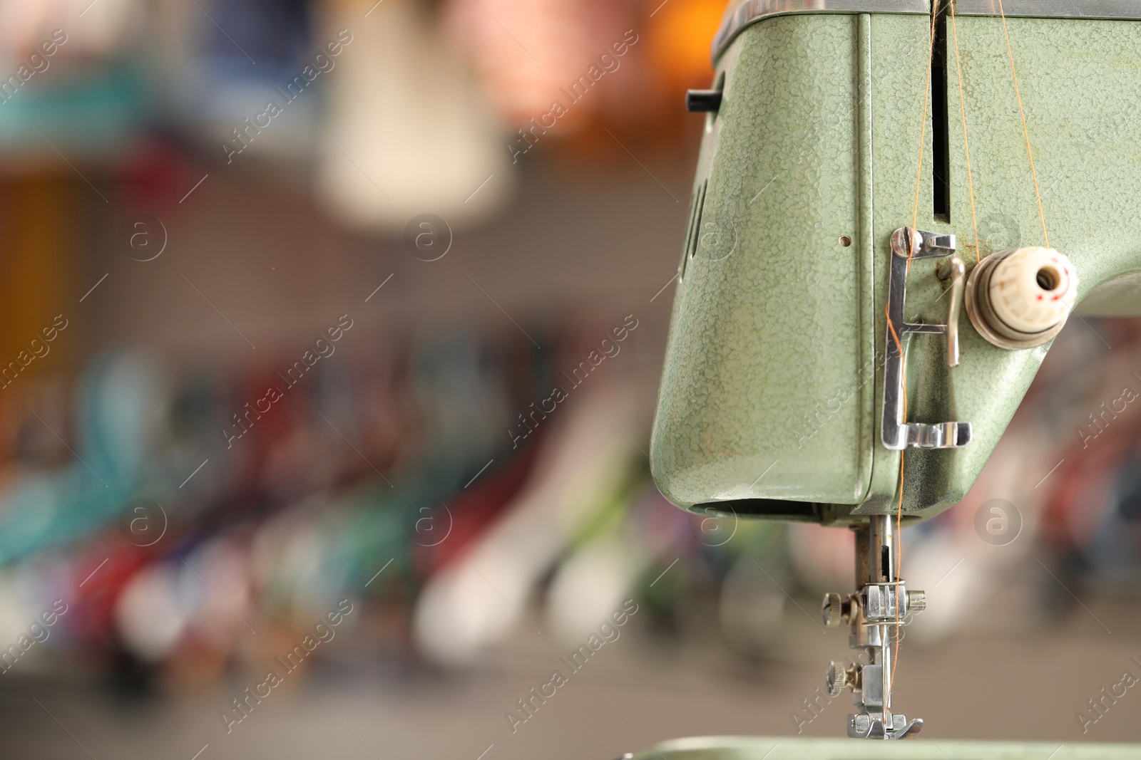 Photo of Vintage sewing machine with thread on blurred background, macro view. Space for text