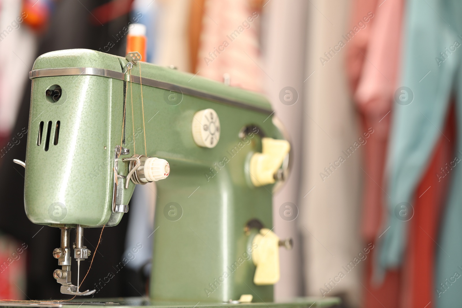 Photo of Vintage sewing machine with thread on blurred background, macro view. Space for text