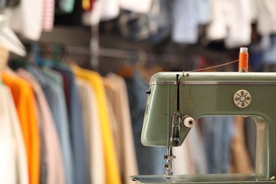 Photo of Vintage sewing machine with thread in workshop. Space for text