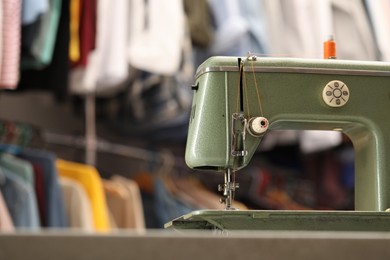 Photo of Vintage sewing machine with thread in workshop. Space for text