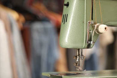 Photo of Vintage sewing machine with thread in workshop, closeup. Space for text