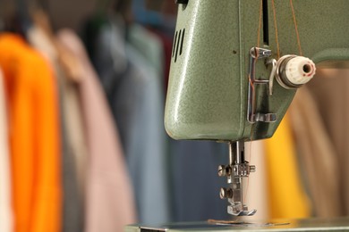 Photo of Vintage sewing machine with thread in workshop, closeup. Space for text