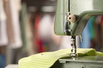 Vintage sewing machine with thread and fabric on blurred background, macro view. Space for text