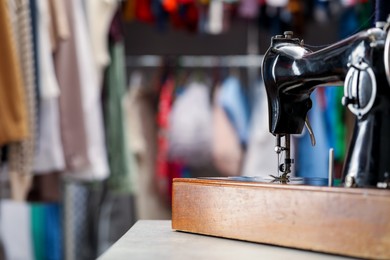 Photo of Vintage sewing machine with thread on table in workshop, space for text