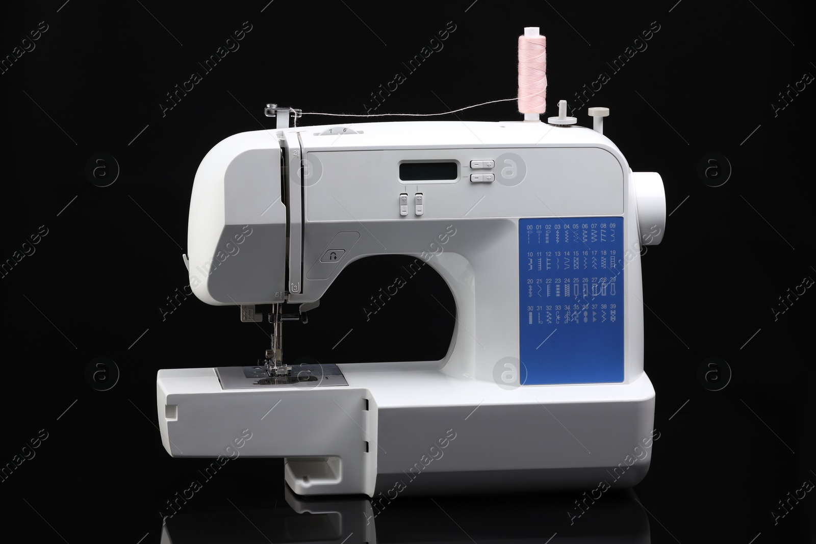 Photo of One sewing machine with spool of thread on black background