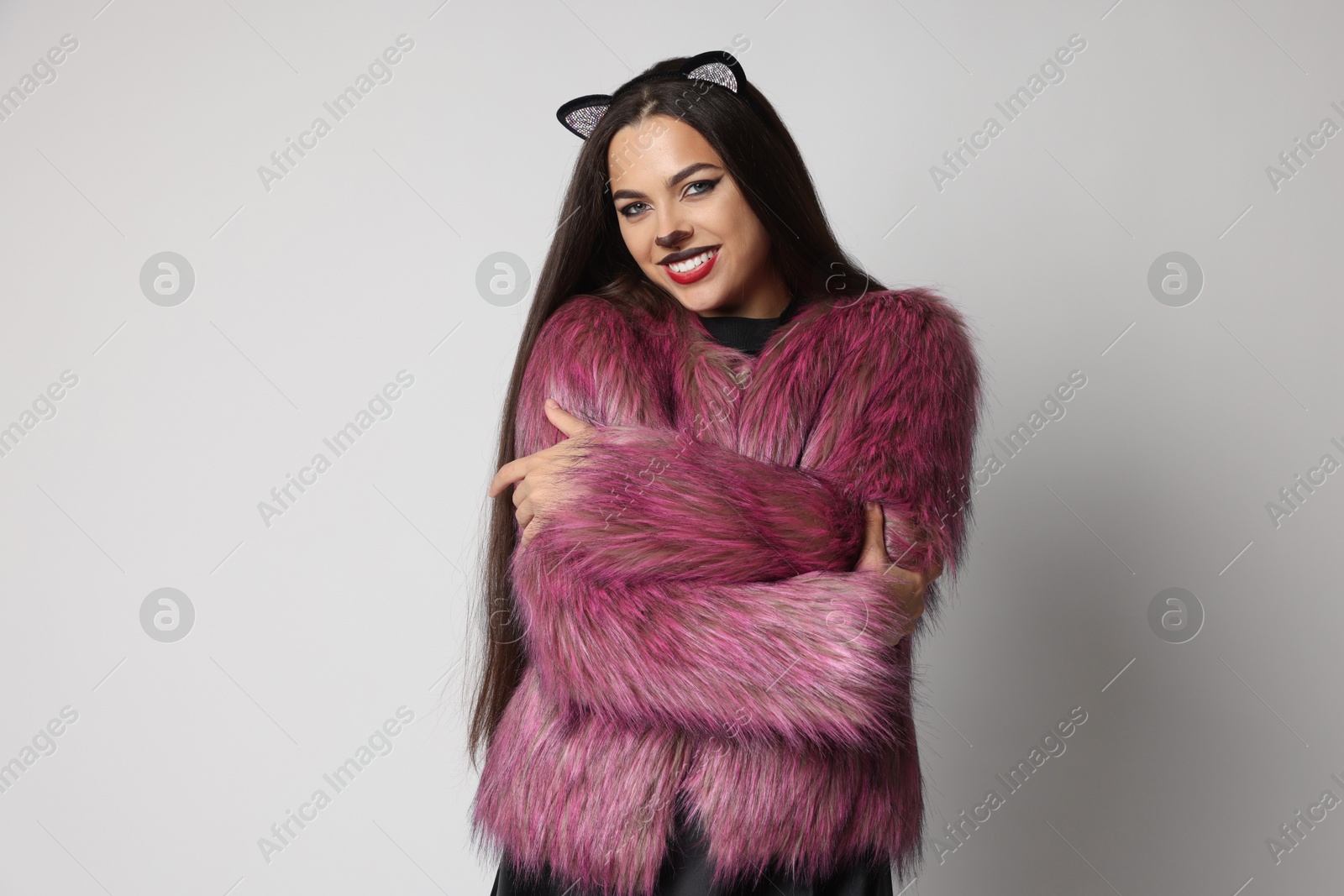 Photo of Smiling woman with cat makeup and ears on white background