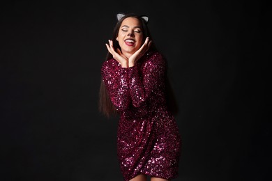 Photo of Excited woman with cat makeup and ears on black background