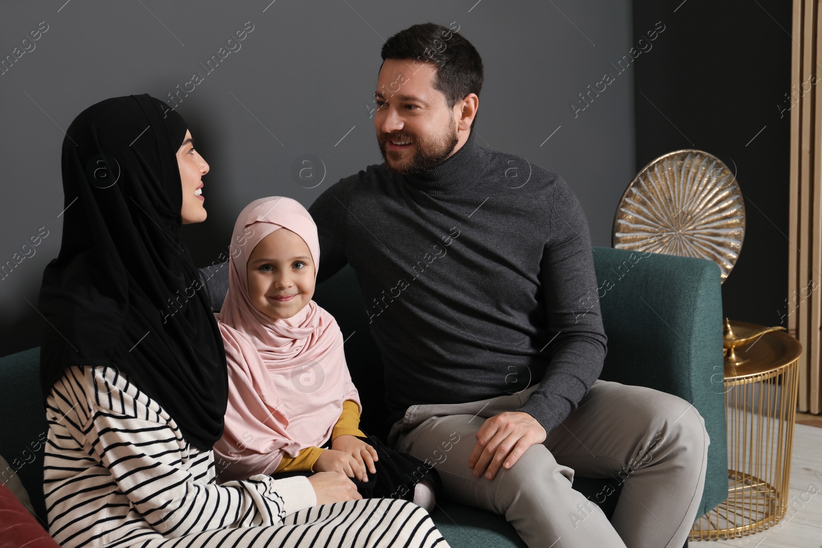 Photo of Happy Muslim family sitting on sofa at home