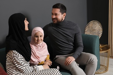 Photo of Happy Muslim family sitting on sofa at home