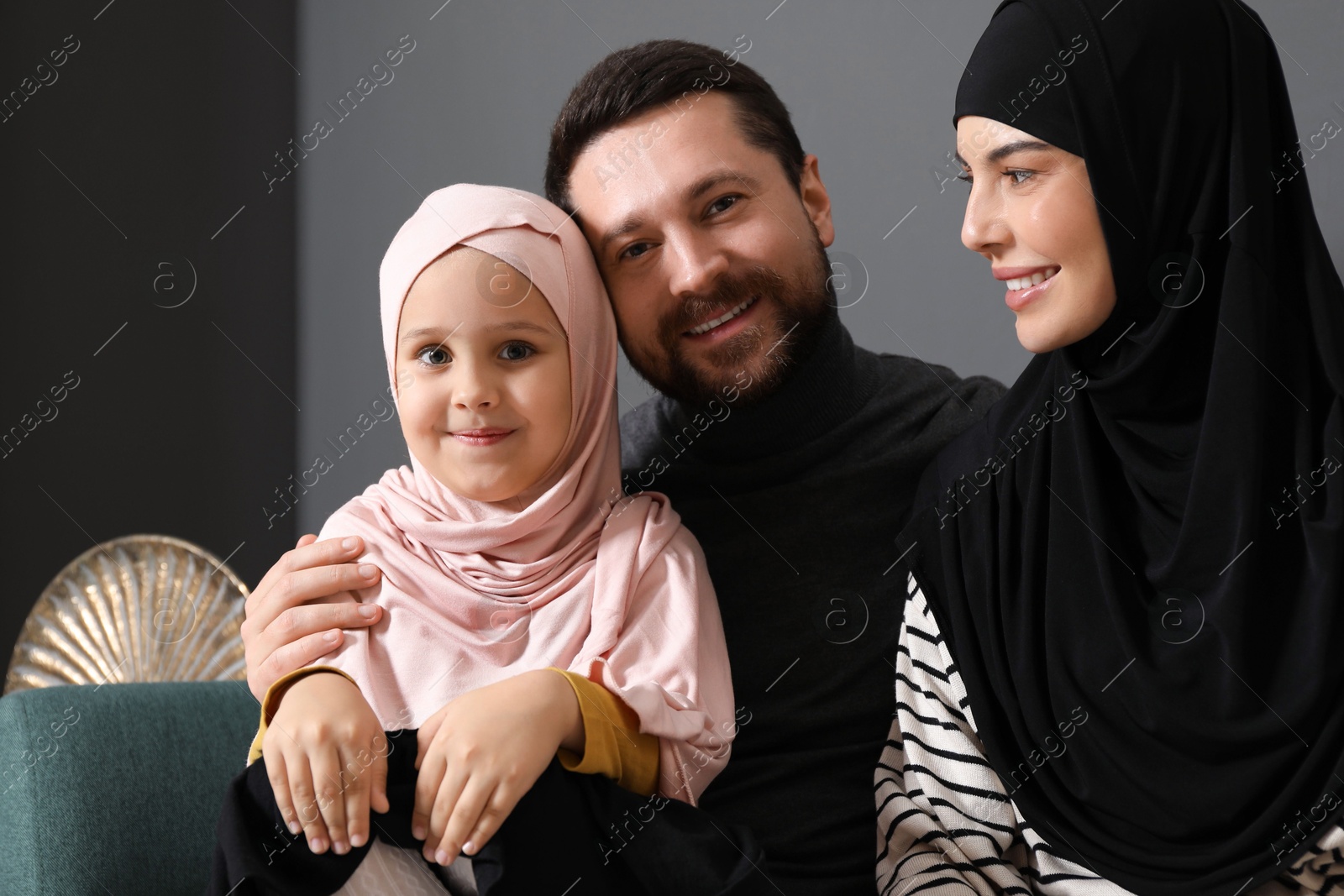 Photo of Happy Muslim family sitting on sofa at home