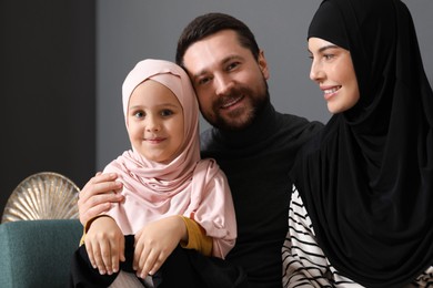 Photo of Happy Muslim family sitting on sofa at home