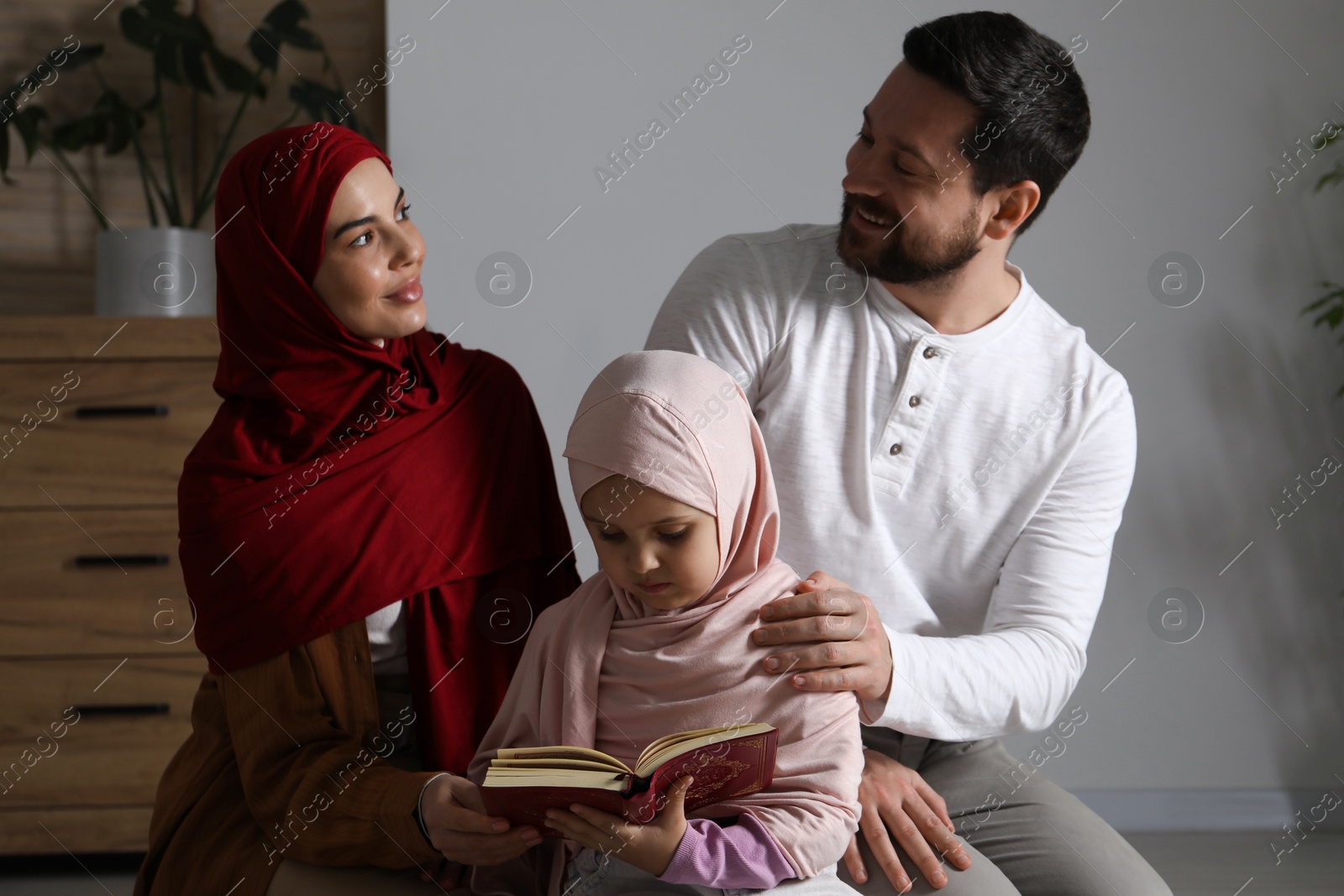 Photo of Muslim family with Quran praying on mat at home