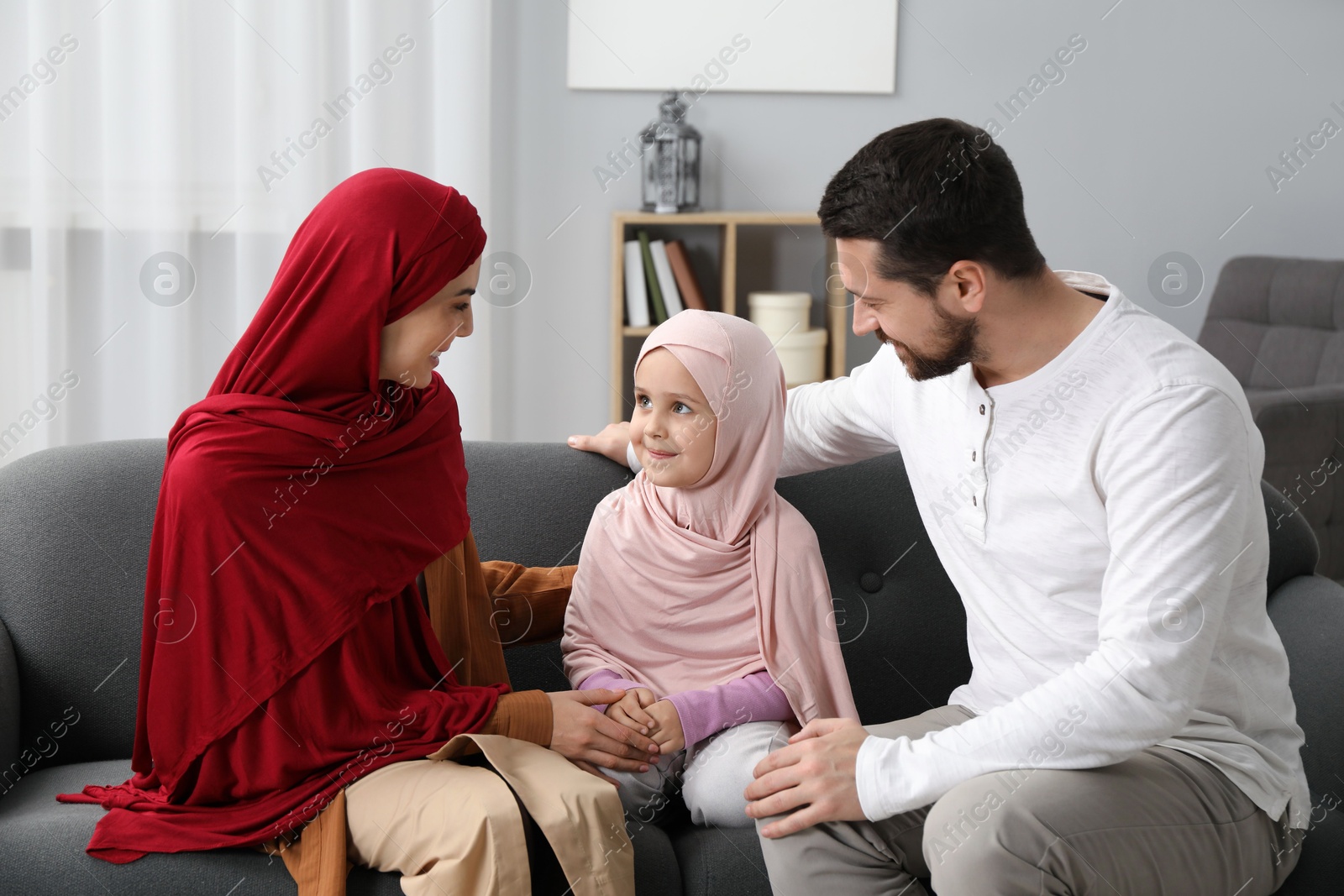 Photo of Happy Muslim family sitting on sofa at home