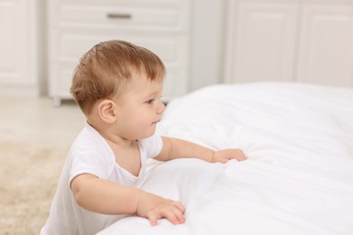 Photo of Sweet little baby near bed at home