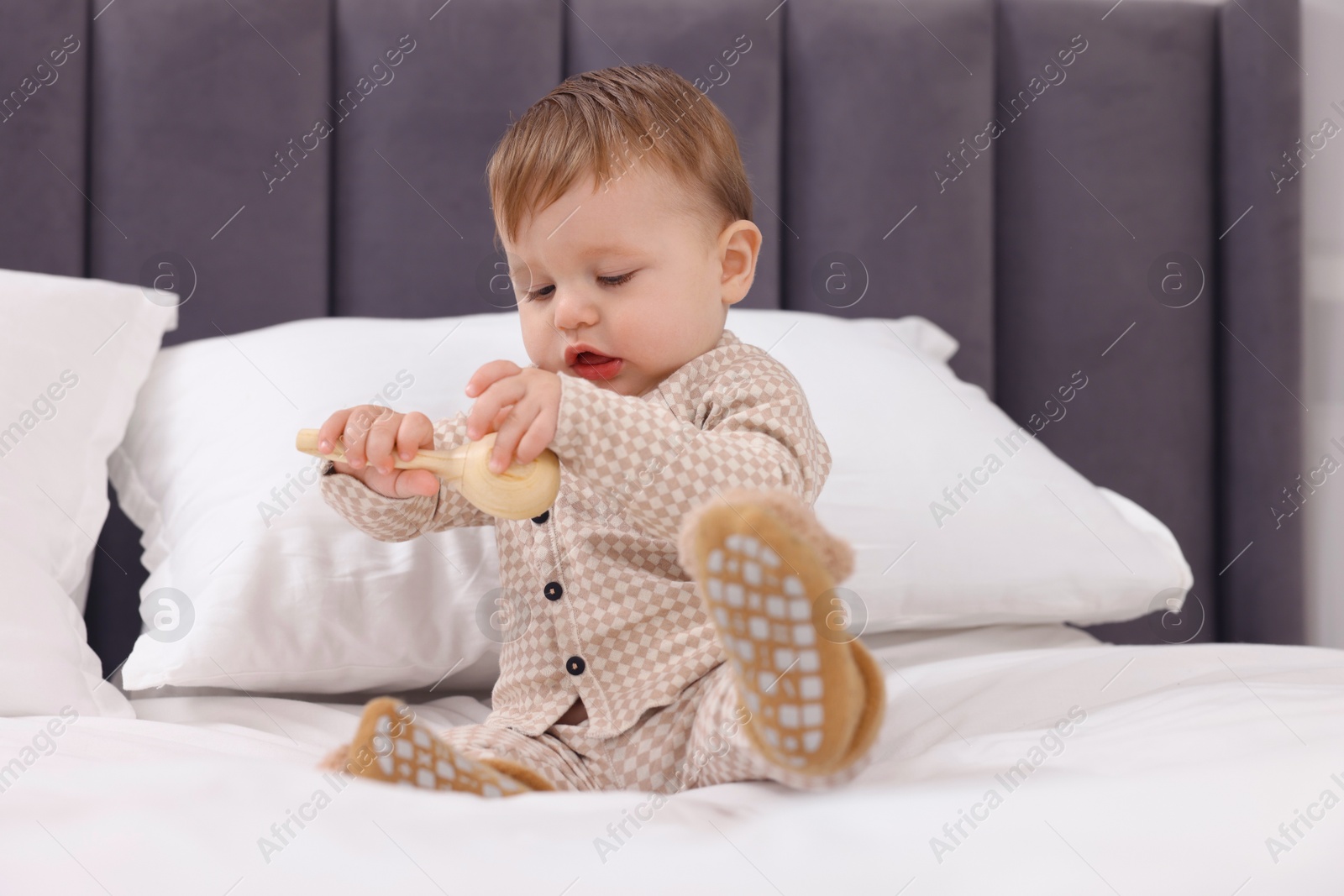 Photo of Cute little baby with toy on bed at home