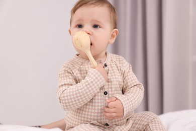 Photo of Adorable little baby with toy on bed at home