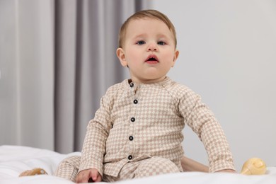 Photo of Adorable little baby with toy on bed at home