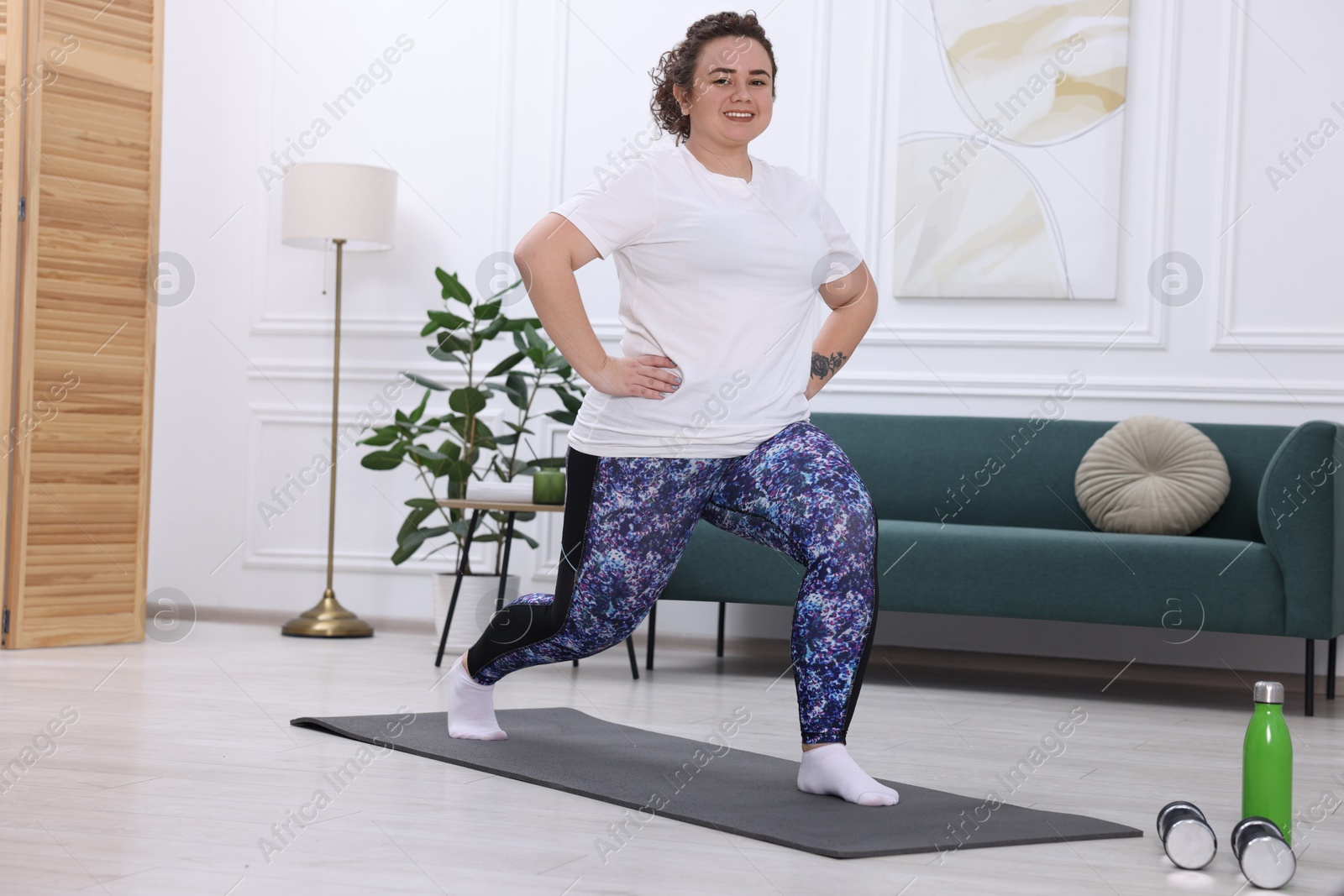 Photo of Plus size woman exercising on fitness mat at home