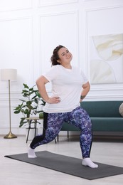 Plus size woman exercising on fitness mat at home