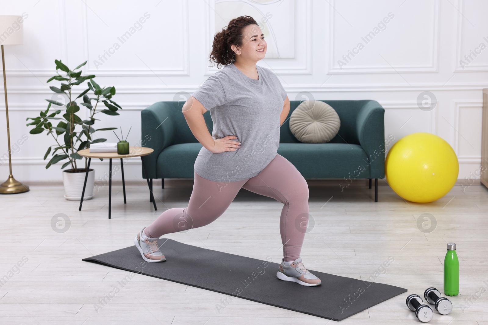 Photo of Plus size woman exercising on fitness mat at home