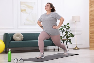 Photo of Plus size woman exercising on fitness mat at home