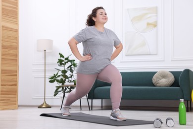 Plus size woman exercising on fitness mat at home