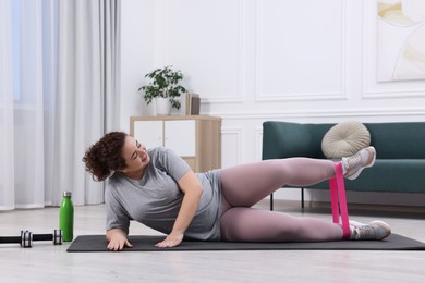 Photo of Woman training with resistance band at home