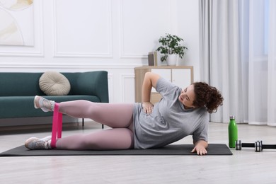 Photo of Woman training with resistance band at home