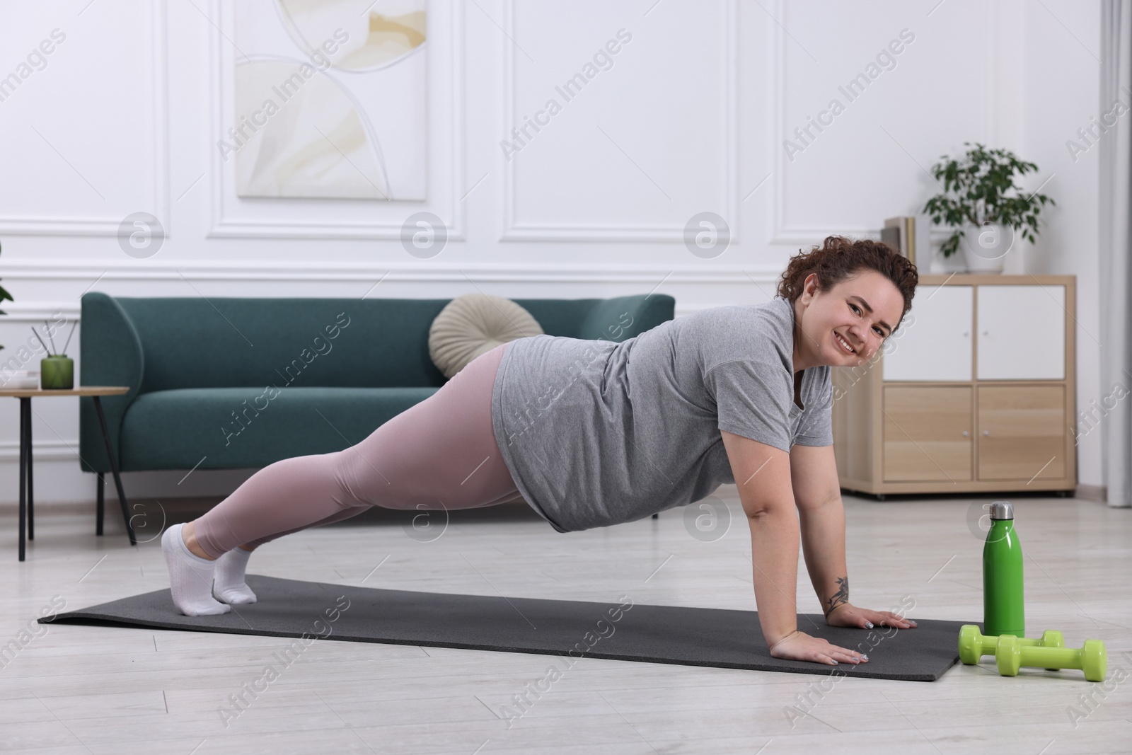 Photo of Woman doing plank exercise on fitness mat at home