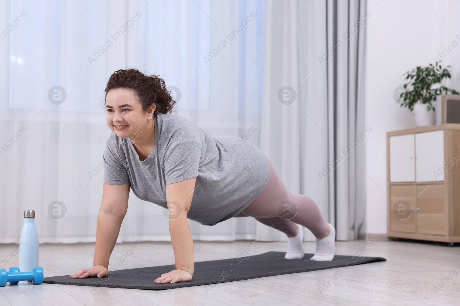 Photo of Woman doing plank exercise on fitness mat at home