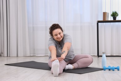 Plus size woman stretching during fitness training at home